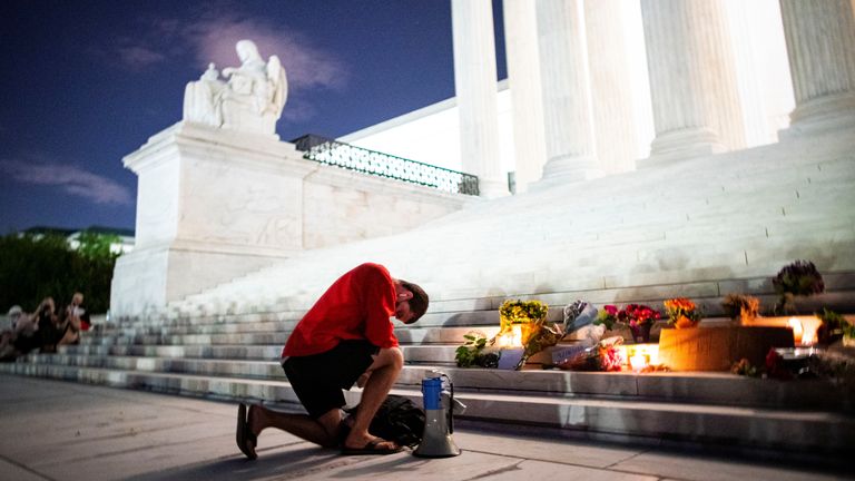 A man kneels at a vigil for Justice Ginsburg