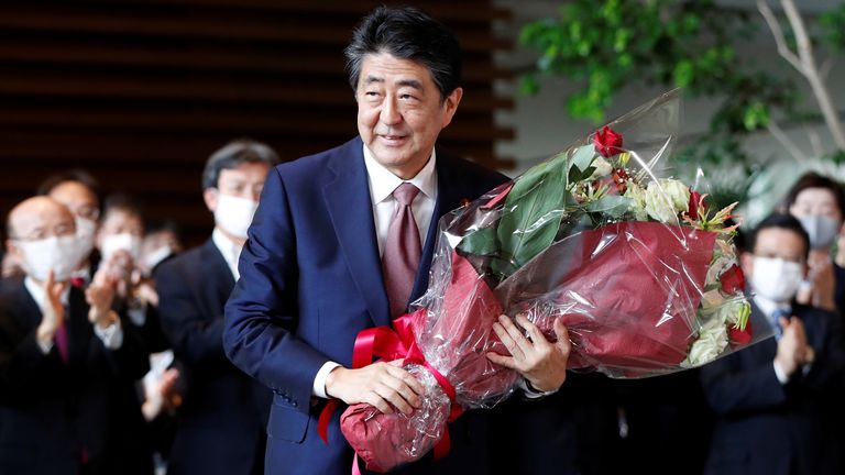 Japan&#39;s outgoing Prime Minister Shinzo Abe holds a bouquet of flowers presented by staff members of the official prime minister&#39;s residence, as he leaves the premises
