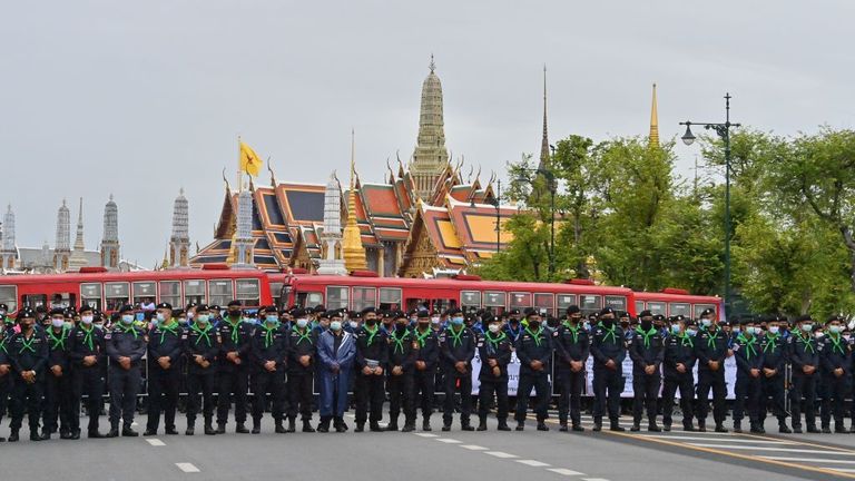 A line of police stand guard in front of the Grand Palace