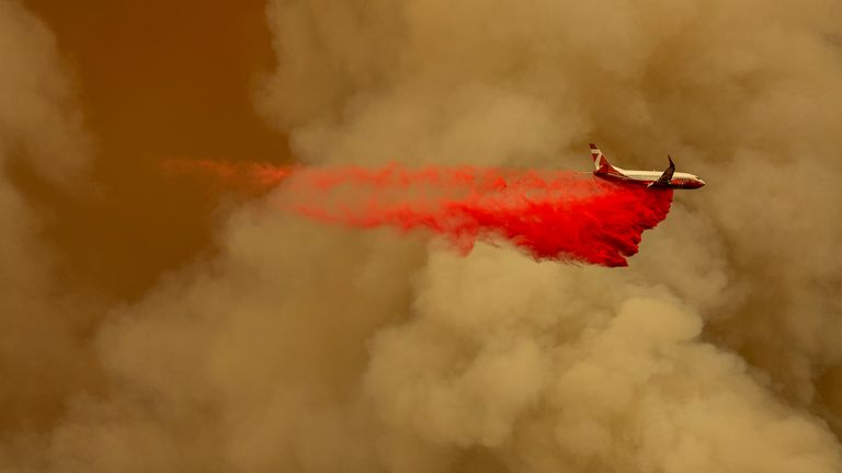 A Coulson 737 firefighting tanker jet drops fire retardant to slow a blaze in the Californian mountains