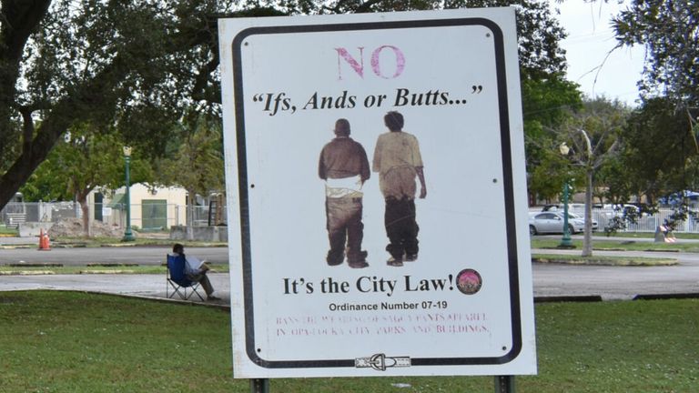 Signs in a park warn passersby about the saggy pants law