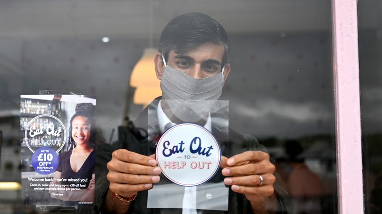 Chancellor of the Exchequer Rishi Sunak places an Eat Out to Help Out sticker in the window of a business during a visit to Rothesay on the Isle of Bute, Scotland.