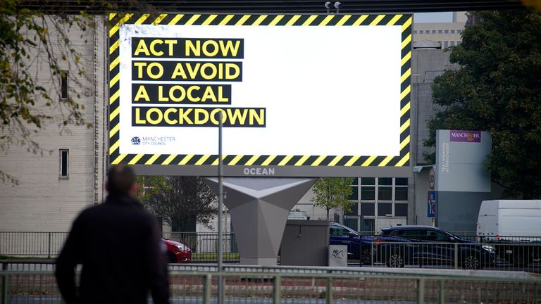 MANCHESTER, ENGLAND - OCTOBER 19:  People make their way to work past an electronic Covid-19 warning sign advises people entering Manchester city centre on October 19, 2020 in Manchester, England. Greater Manchester's leaders including Mayor Andy Burnham will want better financial arrangements for workers affected before they agree for the region to be moved into a Tier 3 Covid-19 lockdown. (Photo by Christopher Furlong/Getty Images)