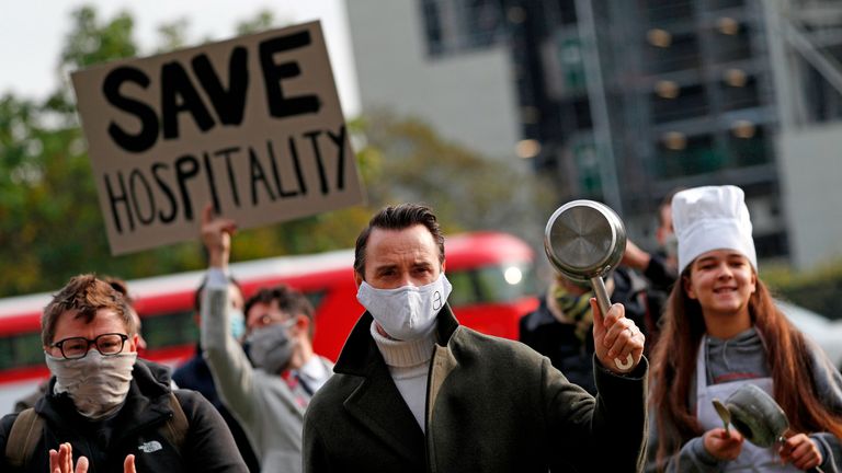 Chef and restaurateur Jason Atherton (C) joins demonstrators from the hospitality industry, some wearing a face mask or covering due to the COVID-19 pandemic, as they gather to protest against the government's new tougher coronavirus restrictions, and to call for more support for their industry, in Parliament Square in central London on October 19, 2020. - Britain's pub industry is bearing the brunt of new restrictions introduced to combat rising coronavirus infection rates, sending stock prices tumbling last Friday. Millions of people in London and across Britain are no longer be able to mix with other households, although those from the same household will still be able to go a pub or restaurant. (Photo by ADRIAN DENNIS / AFP) (Photo by ADRIAN DENNIS/AFP via Getty Images)