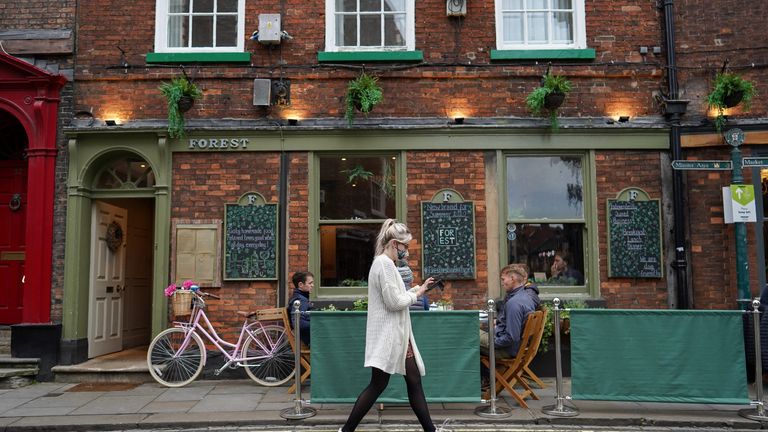 YORK, ENGLAND - OCTOBER 18: A waitress walks to take an order as customers sit at a pavement cafe in York on October 18, 2020 in York, England. York city has become another of England&#8217;s high risk areas placed under 'Tier 2' coronavirus lockdown measures as Government data indicates the R number range for the whole of the UK had increased slightly from between 1.2 and 1.5 last week to 1.3 and 1.5. Most notably the change will introduce a ban on people from different households from mixing anywhere indoors, prompting particular concern within the already badly-affected hospitality industry. (Photo by Ian Forsyth/Getty Images)