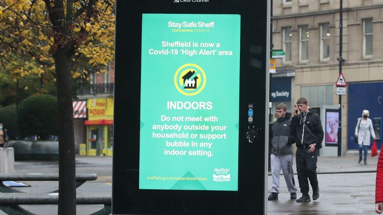 A woman wearing a face mask passes a coronavirus advice sign in Sheffield, as South Yorkshire is the latest region to be placed into Tier 3 coronavirus restrictions, which will come into effect on Saturday.