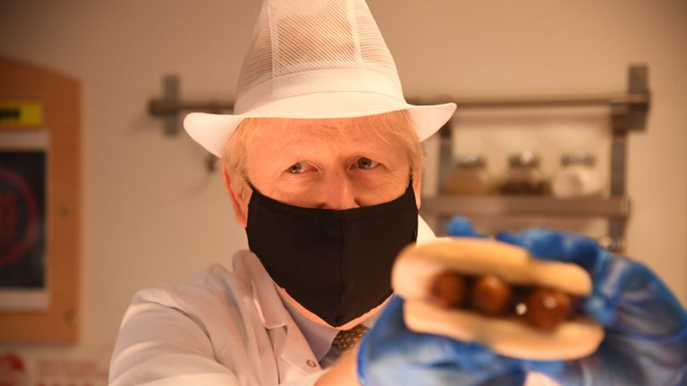 Prime Minister Boris Johnson holds up a roll filled with sausage during a visit to Royal Berkshire Hospital, Reading, to mark the publication of a new review into hospital food.