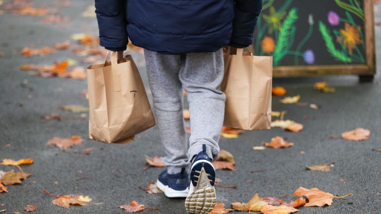 A child collects packed lunch bags from the Watering Can, in Greenbank Park, Liverpool, who are providing free school meals for children over the half term holidays. Local councils and businesses are continuing to pledge free food for children in need during this week's half term break after the Government defeated a Labour motion to extend free school meals provision in England over the holidays.