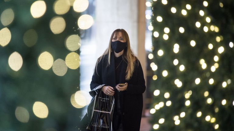 A woman wearing a face mask walks past Christmas lights outside a department store in central London. A new three-tier system of alert levels for England has been implemented following rising coronavirus cases and hospital admissions.