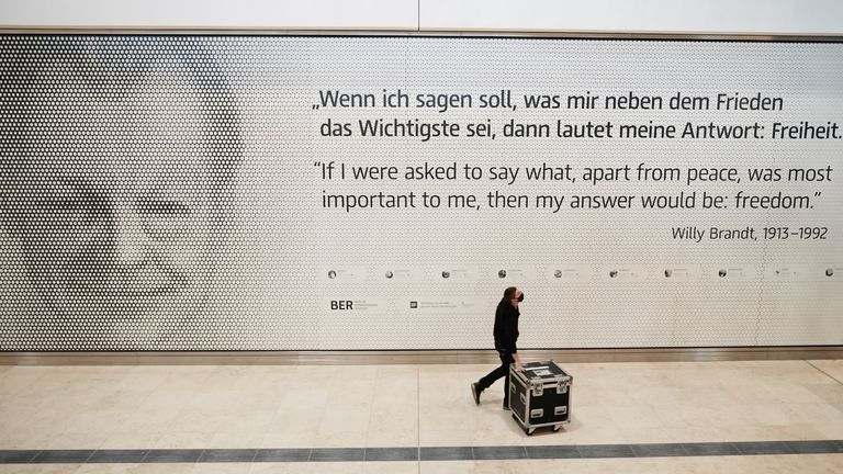 An employee walks inside Terminal 1 of the Berlin-Brandenburg International Airport Willy-Brandt (BER) passing a photo of former German Chancellor Willy Brandt in Schoenefeld near Berlin on October 27, 2020. - Nine years late and with excess budget The new international airport in the Berlin region will finally open on October 31, 2020, amid a global pandemic that has paralyzed air travel.  (Photo by Michael Kappeler / POOL / AFP) (Photo by MICHAEL KAPPELER / POOL / AFP via Getty Images)