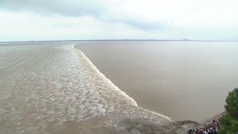 The tidal bore occurs due to the unique geography of the trumpet-shaped bay, which allows sea water to flow in, but not ebb