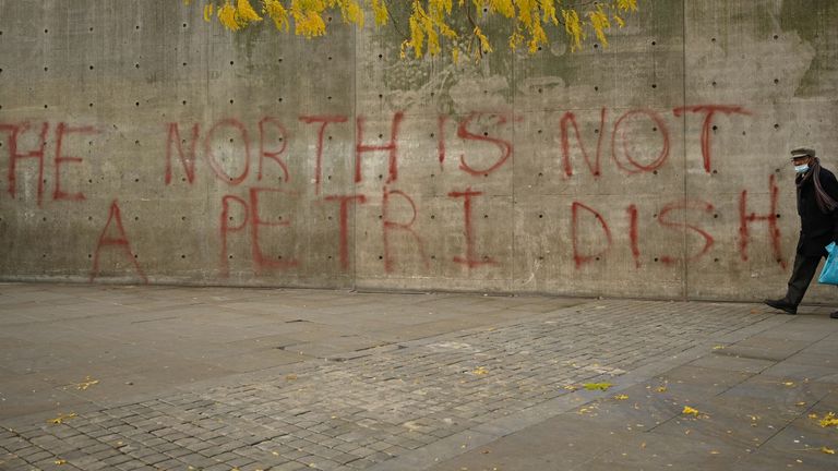 A man wearing a face-mask walks past graffiti in central Manchester