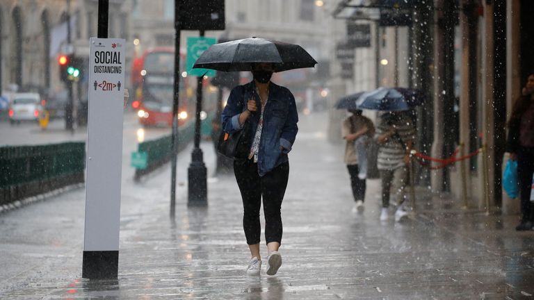 A pedestrian wearing PPE (personal protective equipment), of a face mask or covering as a precautionary measure against COVID-19, shelters under an umbrella they are caught in a downpour of rain on Oxford Street in London on June 17, 2020, as lockdown restrictions imposed to stem the spread of the novel coronavirus continue to be relaxed. - Britain&#39;s annual inflation rate slid to 0.5 percent in May, the lowest level in four years, as the country&#39;s coronavirus lockdown dampens prices, official da