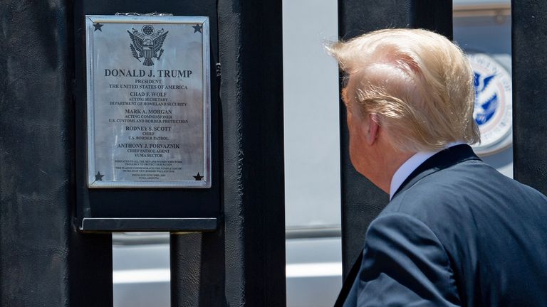 Mr Trump looks a plaque marking the 200th mile of border wall construction in San Luis, Arizona