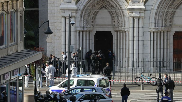 French members of the elite tactical police unit RAID enter to search the Basilica of Notre-Dame de Nice as forensics officers wait outside after a knife attack in Nice on October 29, 2020. - A man wielding a knife outside a church in the southern French city of Nice slit the throat of one person, leaving another dead and injured several others in an attack on Thursday morning, officials said. The suspected assailant was detained shortly afterwards, a police source said, while interior minister 