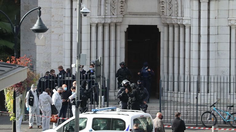 French members of the elite tactical police unit RAID enter to search the Basilica of Notre-Dame de Nice as forensics officers wait outside after a knife attack in Nice on October 29, 2020. - A man wielding a knife outside a church in the southern French city of Nice slit the throat of one person, leaving another dead and injured several others in an attack on Thursday morning, officials said. The suspected assailant was detained shortly afterwards, a police source said, while interior minister 