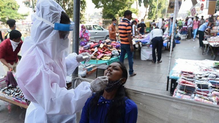 A health worker collects a swab sample from a woman to test for the Covid-19 coronavirus at a market place in Ahmedabad on October 29, 2020. - India on October 29 passed eight million coronavirus cases, with the world&#39;s second-worst-hit country bracing for a possible second wave ahead of winter and a series of religious festivals. (Photo by SAM PANTHAKY / AFP) (Photo by SAM PANTHAKY/AFP via Getty Images)