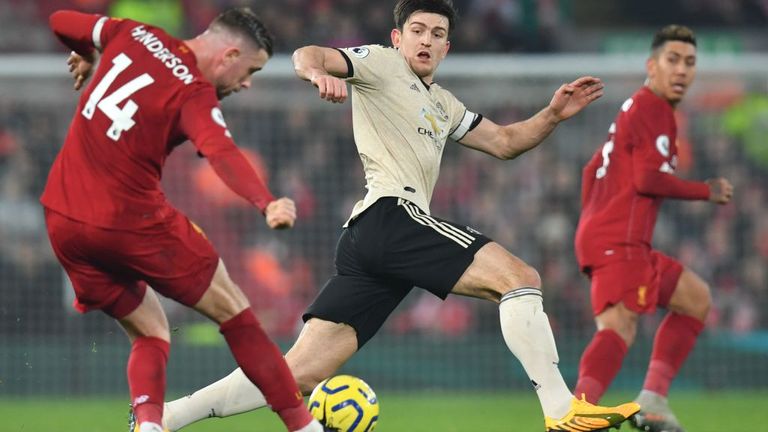 Liverpool midfielder Jordan Henderson, left, is making a pass as Manchester United's Harry Maguire attempts an interception