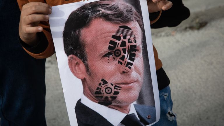 A boy  in Istanbul holds a poster a footprint on the French president&#39;s face