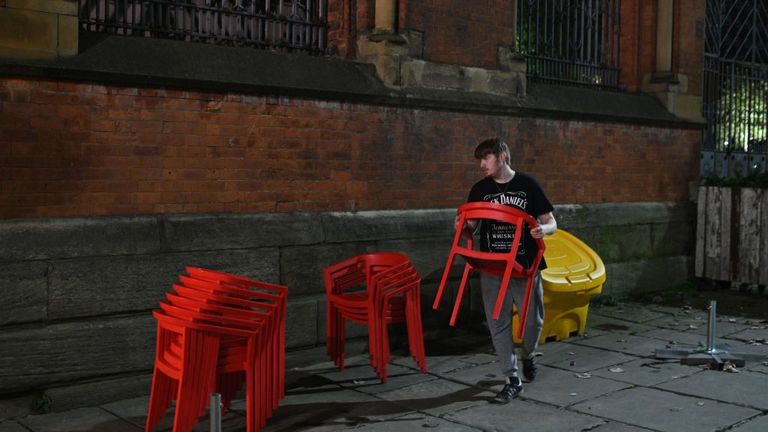 A bar worker removes chairs in Manchester as pubs and restaurants face tougher restrictions 