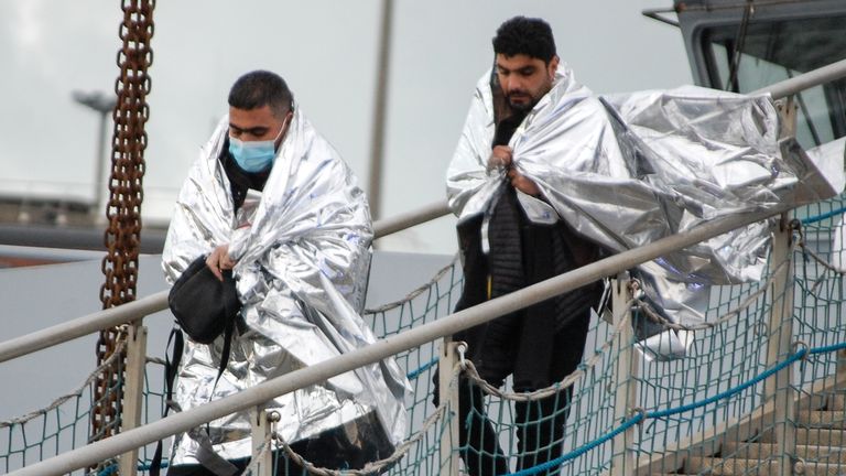 Two men walk returning to Calais after being picked up with 15 others  by a rescue boat