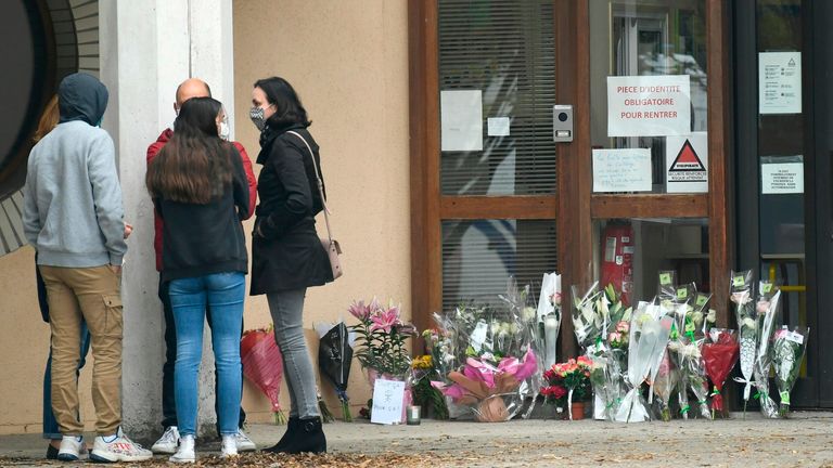 Flowers have been placed at the entrance of a middle school in Conflans-Sainte-Honorine, 30kms northwest of Paris, on October 17, 2020, after a teacher was decapitated by an attacker who has been shot dead by policemen