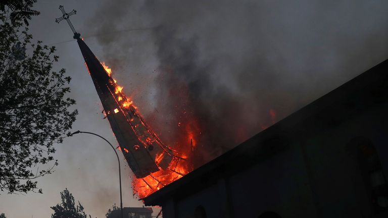 A burning church spire falls to the ground after being set on fire in the Chilean capital 