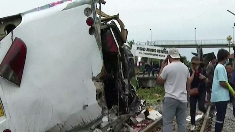 Authorities survey the wreckage from a train crash, after it collided with a bus, in Thailand