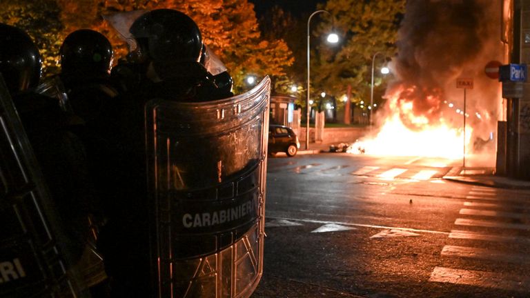 Police officers stand guard as protesters set fire to public property during an anti government demonstration 