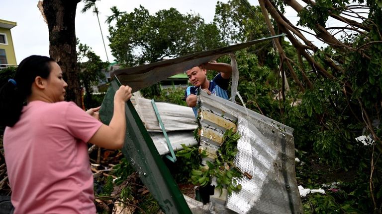 A couple clears debris outside their house