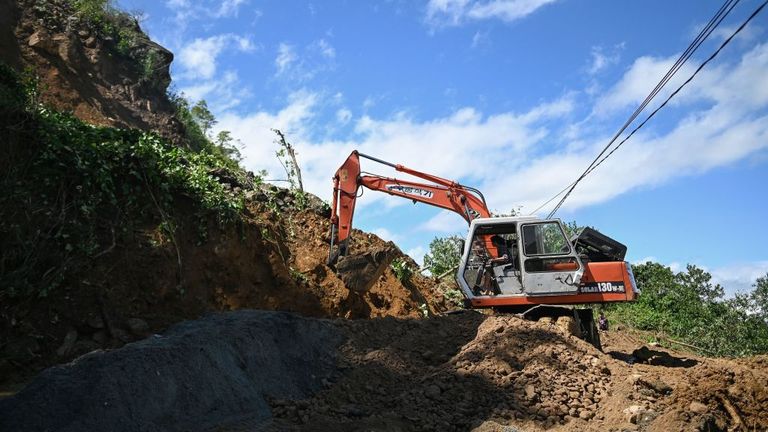 A worker in a bulldozer clears debris from a landslide that blocked a road