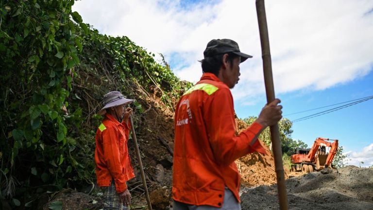 Workers clear debris from a landslide that blocked a road 
