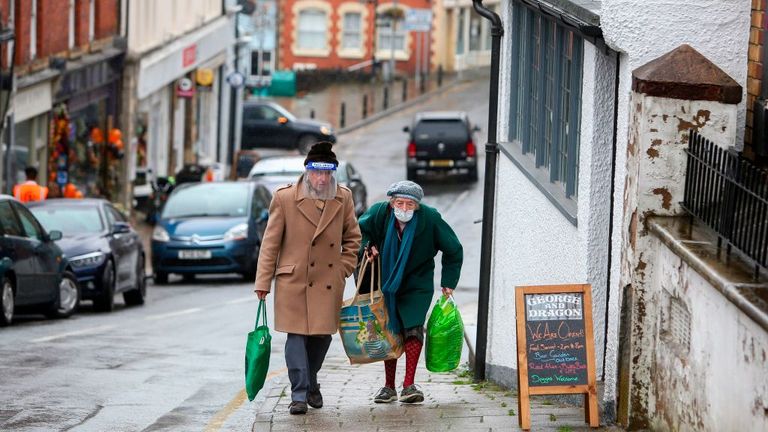 An elderly couple are seen wearing a visor and mask in Knighton, Wales