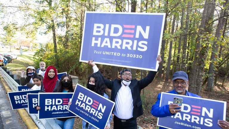 NORCROSS, GA - NOVEMBER 3: Gwinnett County voters, including Menar Hague (C), wave Biden-Harris campaign posters at the Lucky Shoals Park polling station entrance on November 3, 2020 in Norcross, Georgia.  After a record turnout in early voting, Americans head to the polls on the last day to cast their vote for current US President Donald Trump or Democratic nominee Joe Biden in the 2020 presidential election. (Photo by Jessica McGowan / Getty Images)