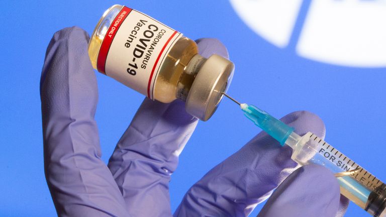 A woman holds a small bottle with a "Vaccination against Coronavirus COVID-19" sticker and a medical syringe in front of display Pfizer logo taken in this illustration, 30 October 2020. REUTERS / Dado Ruvic