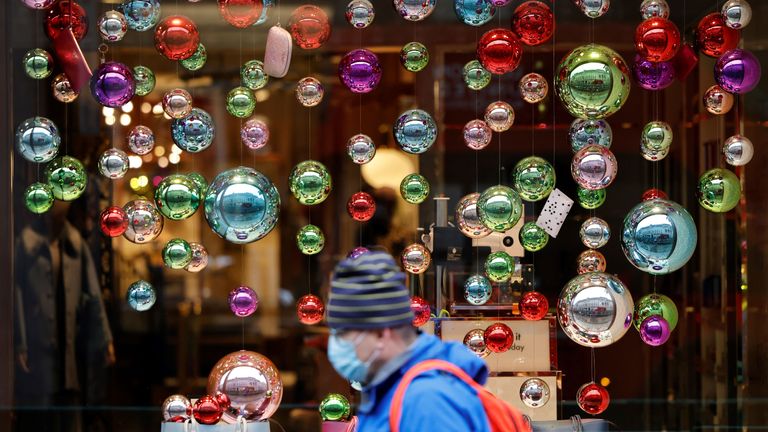 People walk in the rain past Christmas decorations in central London on November 20, 2020, as life under a second lockdown continues in England. - The current lockdown in England has shuttered restaurants, gyms and non-essential shops and services until December 2, with hopes business could resume in time for Christmas. (Photo by Tolga Akmen / AFP) (Photo by TOLGA AKMEN/AFP via Getty Images)
