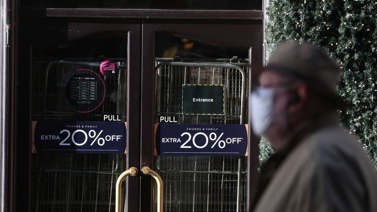 A man walks past the closed House of Fraser store on Buchanan Street in Glasgow on the first day after eleven local council areas in Scotland moved into Level 4 restrictions to slow the spread of coronavirus.