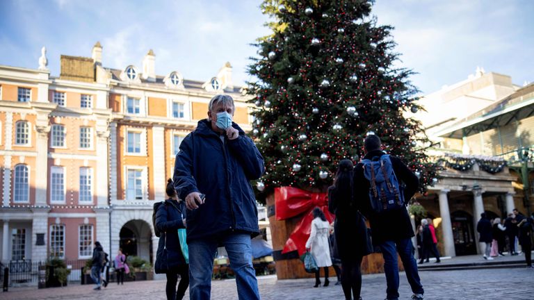 Pedestrians wearing a protective face covering to combat the spread of the coronavirus, walk past a Christmas tree in Covent Garden in central London, on November 22, 2020, as the four-week national shutdown imposed in England continues, forcing people to stay home and businesses to close owing to a second wave of the Covid-19 pandemic. - British Prime Minister Boris Johnson will confirm that coronavirus lockdown restrictions across England are to end on December 2, his office said Saturday. The lockdown will be followed by a return to a three-tiered set of regional restrictions as part of the government's "COVID Winter Plan", it added in a statement. (Photo by Tolga Akmen / AFP) (Photo by TOLGA AKMEN/AFP via Getty Images)