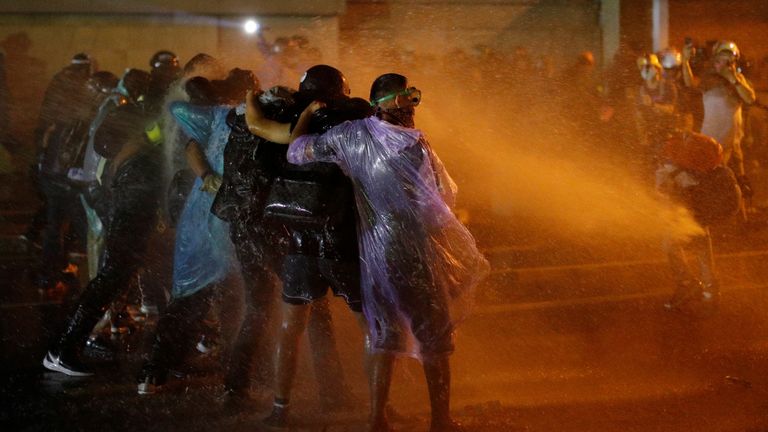 Demonstrators form a line as they protect themselves from water cannons during an anti-government protest as lawmakers debate on constitution change, outside of the parliament in Bangkok, Thailand, November 17, 2020. REUTERS/Jorge Silva