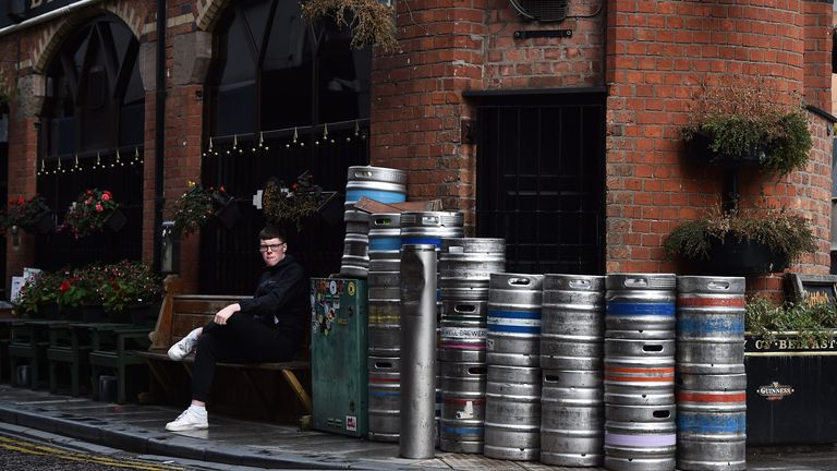 A customer is seen sitting outside Bittles bar beside beer kegs in Belfast city centre on October 14, 2020 in Belfast, Northern Ireland. 