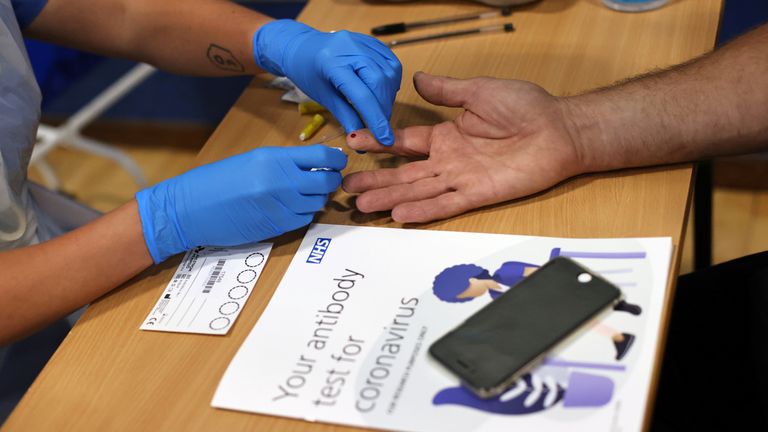 A worker takes a blood sample from a man during a clinical trial 