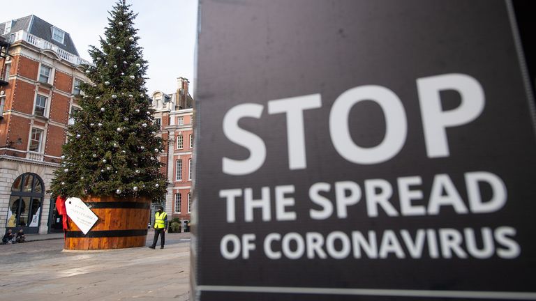 A Christmas tree is seen alongside coronavirus signage in Covent Garden, London, as England continues a four week national lockdown to curb the spread of coronavirus