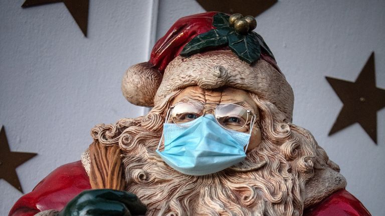 23 November 2020, Lower Saxony, Delmenhorst: A Santa Claus was put on a protective mask. For months the Borchart family did handicrafts and decorations. Now their house is lit up right up to the top of the roof. Photo: Sina Schuldt/dpa
