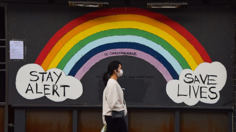 A woman wearing a face mask as a precaution walks past a Stay Alert, Save Lives rainbow sign in Soho. England is set to enforce a tough tier system once the lockdown ends on 2 December. (Photo by Vuk Valcic / SOPA Images/Sipa USA)