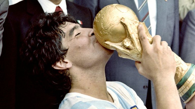 Argentina&#39;s soccer star team captain Diego Maradona kisses the World Soccer Cup won by his team after a 3-2 victory over West Germany on June 29, 1986 at the Azteca stadium in Mexico City watched by Mexican President Miguel de La Madrid (L) and West German Chancellor Helmut Kohl. (Photo by STAFF / AFP) (Photo by STAFF/AFP via Getty Images)