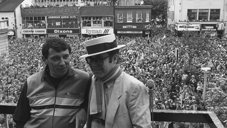 Watford Football Club Chairman Elton John wearing the club scarf with team manager Graham Taylor on a balcony overlooking a crowd of well wishers. It was the clubs first appearance in their 93 year history. Date taken: 20-May-1984