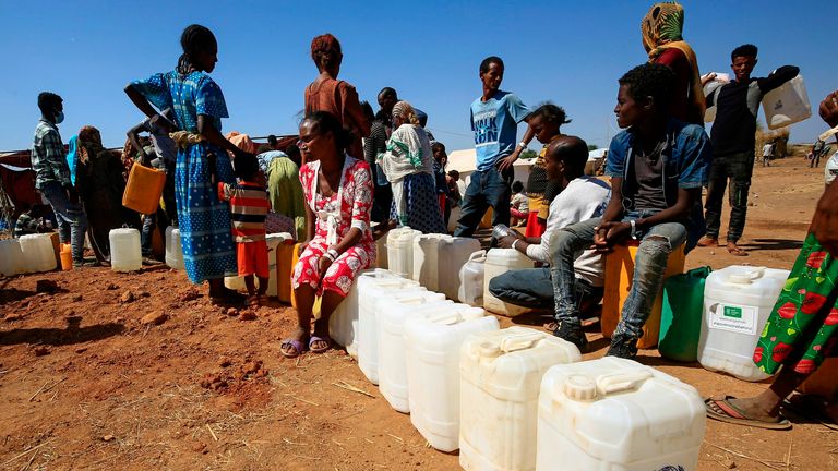 Ethiopian refugees fill bottles and containers with water at Um Raquba camp in Sudan