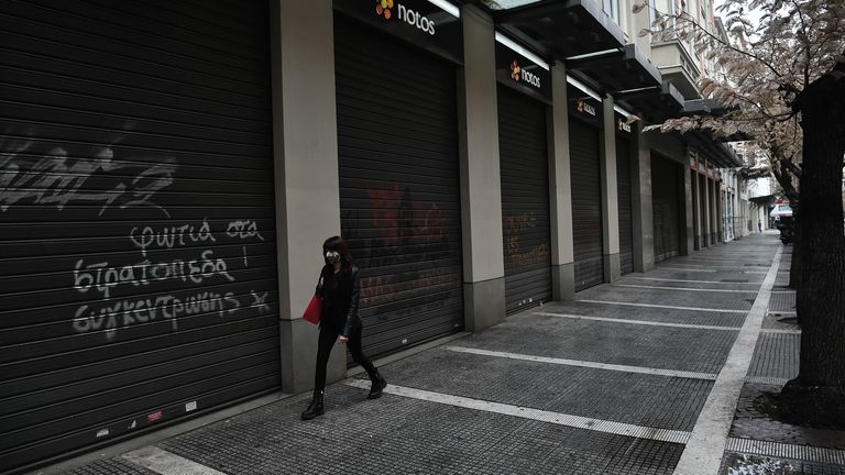 A woman wearing a protective face mask walks next to closed shops in Thessaloniki on November 3, 2020. - Greece announced a two-week lockdown on November 2 on its second largest city of Thessaloniki to try to contain a spike in coronavirus cases. Everything will remain closed, except for schools, and those wanting to leave their homes will have to seek permission via text message. (Photo by Sakis MITROLIDIS / AFP) (Photo by SAKIS MITROLIDIS/AFP via Getty Images)