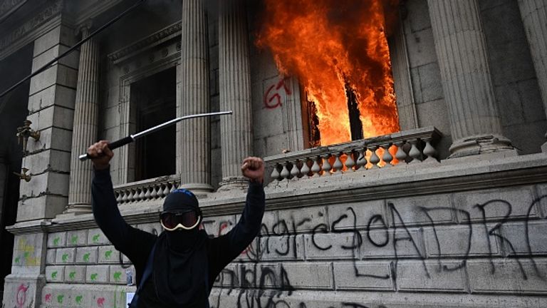 A protester celebrates as the congress building burns behind him