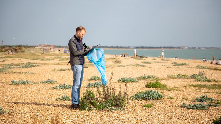 A volunteer is seen picking up trash and taking note of what he finds.  Photo: Marine Conservation Society